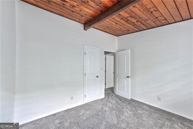 empty room featuring carpet flooring, wood ceiling, and beamed ceiling