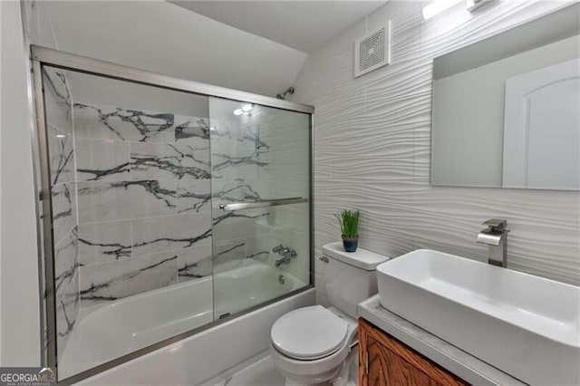 full bathroom with vanity, shower / bath combination with glass door, decorative backsplash, toilet, and tile walls