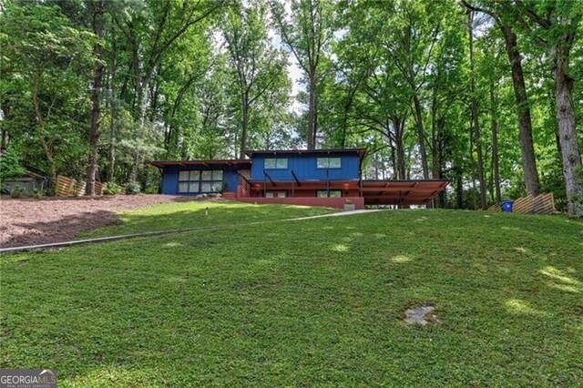 rear view of house featuring a yard and a wooden deck