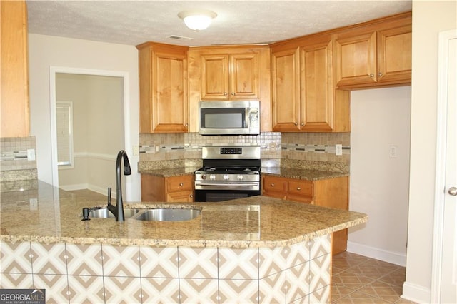 kitchen featuring stainless steel appliances, sink, backsplash, kitchen peninsula, and light stone counters