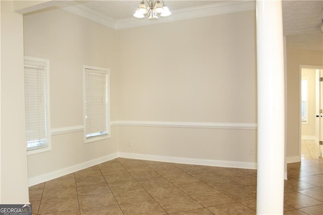 empty room with tile patterned flooring, crown molding, and a notable chandelier