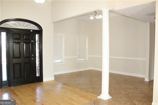 entryway featuring wood-type flooring, ornate columns, and a notable chandelier