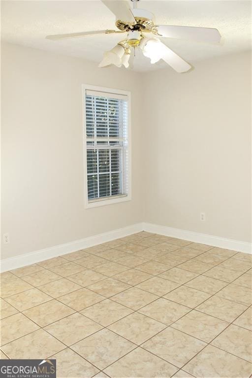 tiled empty room featuring ceiling fan