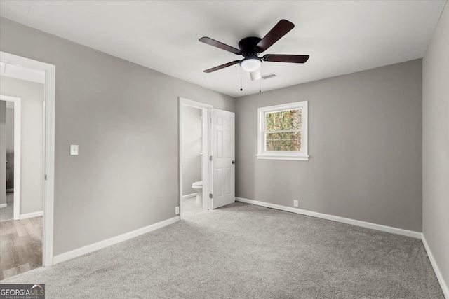 unfurnished bedroom with ceiling fan, light colored carpet, and ensuite bathroom