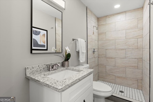 bathroom with tiled shower, vanity, and toilet