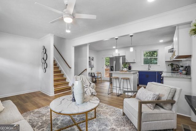 living room featuring dark hardwood / wood-style floors, ceiling fan, crown molding, and sink