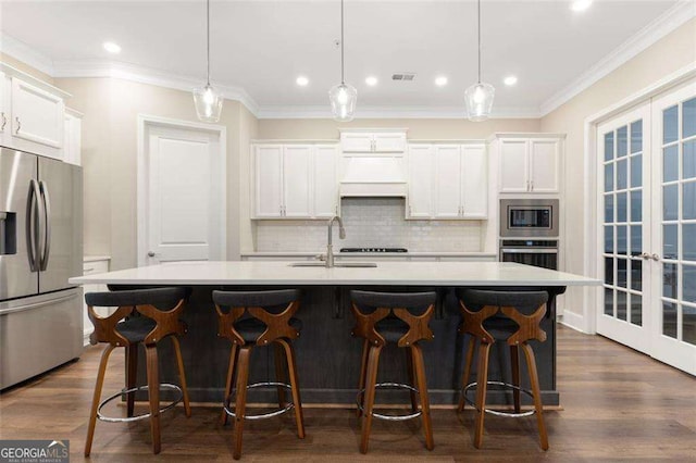 kitchen with white cabinetry, a center island with sink, pendant lighting, and appliances with stainless steel finishes