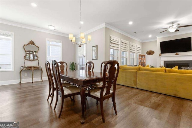 dining area with ceiling fan with notable chandelier, dark wood-type flooring, and crown molding