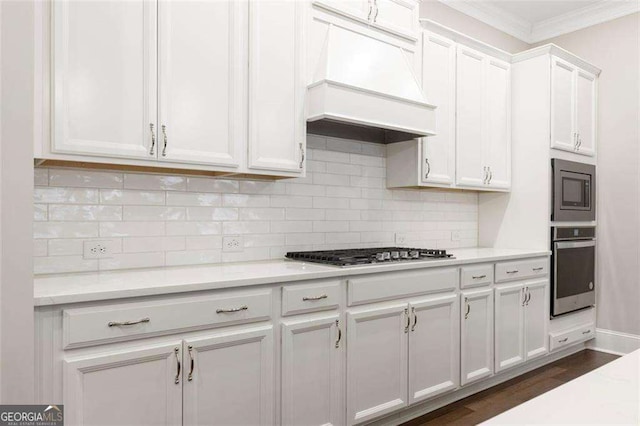 kitchen with custom exhaust hood, crown molding, dark hardwood / wood-style flooring, white cabinetry, and stainless steel appliances