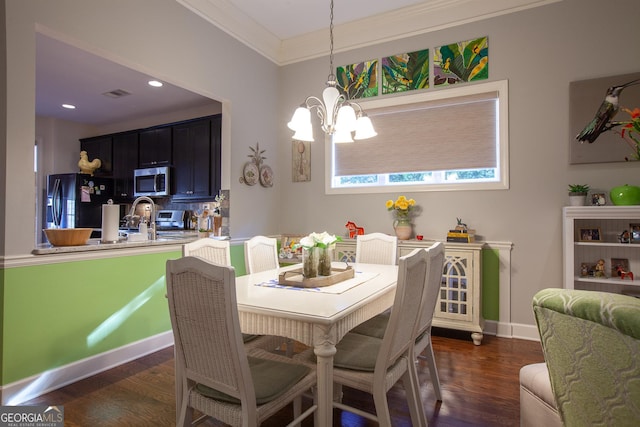 dining space featuring crown molding, sink, dark hardwood / wood-style floors, and an inviting chandelier