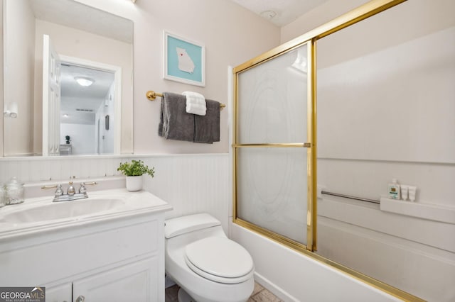 full bathroom featuring toilet, combined bath / shower with glass door, and vanity