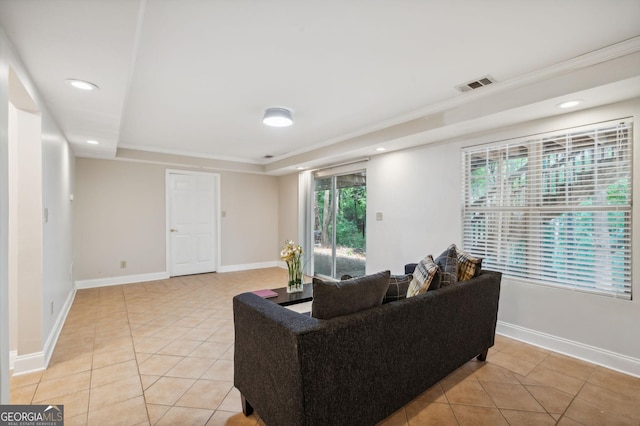 tiled living room featuring a tray ceiling and ornamental molding