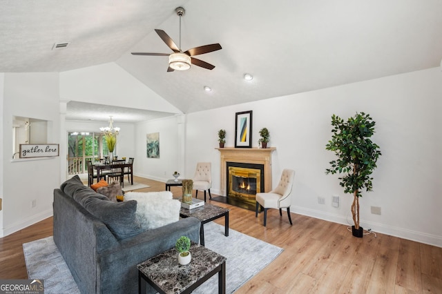 living room featuring light hardwood / wood-style flooring, ceiling fan with notable chandelier, and lofted ceiling