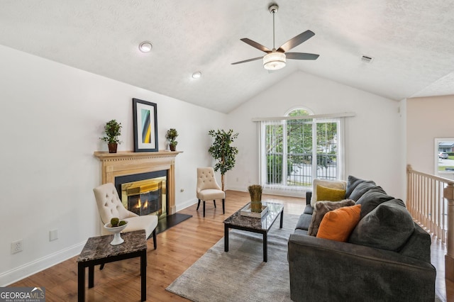 living room featuring a textured ceiling, hardwood / wood-style flooring, ceiling fan, and lofted ceiling