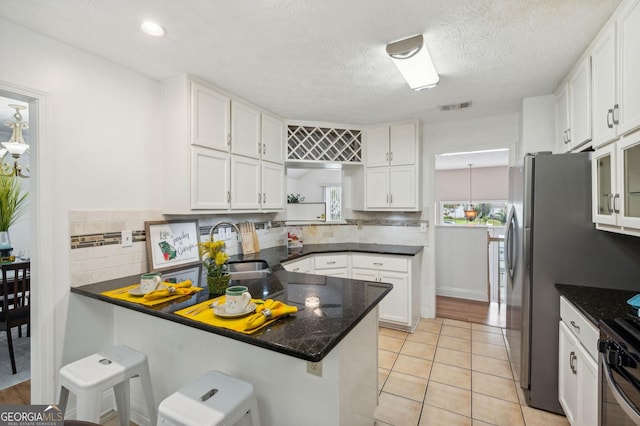 kitchen with a kitchen bar, kitchen peninsula, white cabinetry, and sink