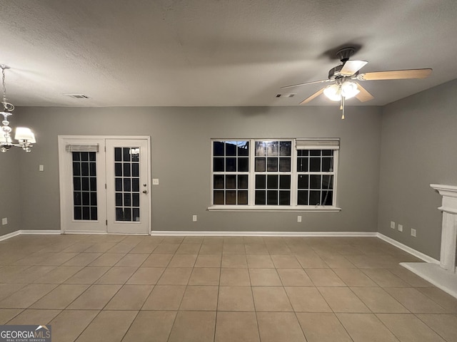 tiled spare room with ceiling fan with notable chandelier and a textured ceiling