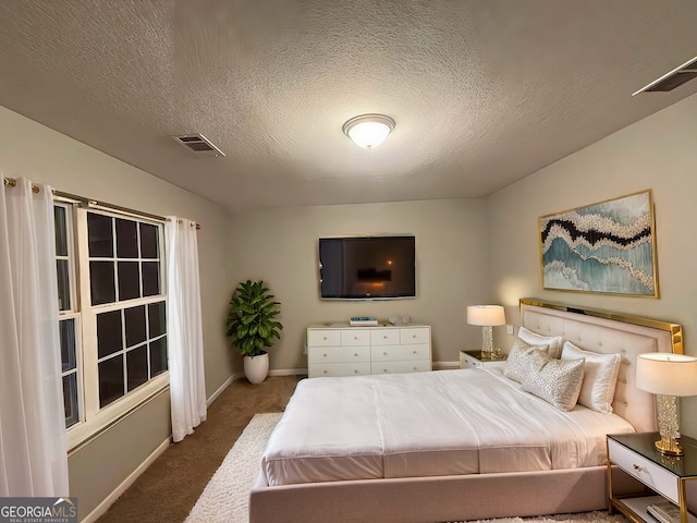 bedroom featuring a textured ceiling and dark carpet