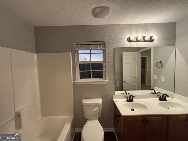 full bathroom featuring toilet, vanity, a textured ceiling, and washtub / shower combination