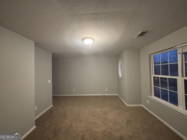 empty room featuring a textured ceiling and carpet