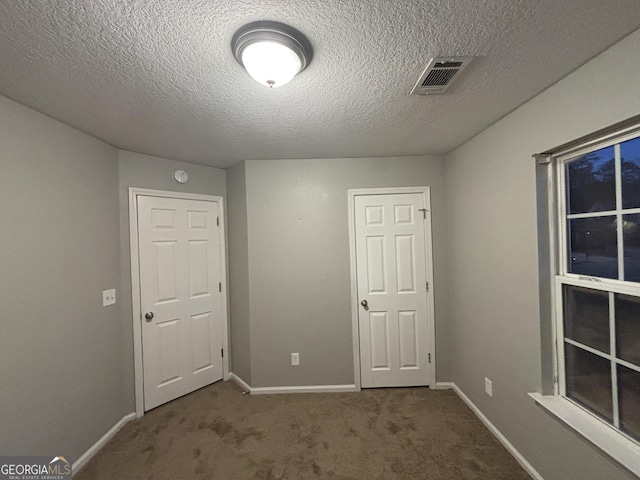 empty room featuring a textured ceiling and carpet