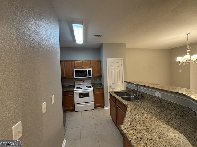 kitchen featuring decorative light fixtures, a notable chandelier, light tile patterned floors, white range with electric cooktop, and sink