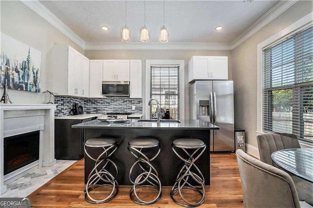 kitchen with sink, hanging light fixtures, a kitchen breakfast bar, a kitchen island, and appliances with stainless steel finishes