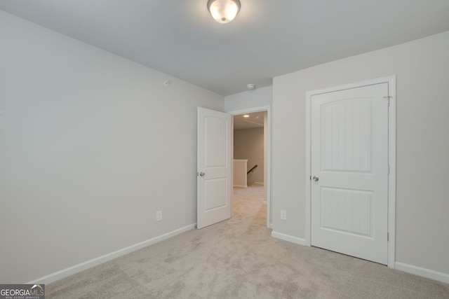 unfurnished bedroom featuring light carpet and a closet