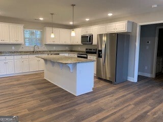 kitchen featuring white cabinets, a center island, stainless steel appliances, and decorative light fixtures