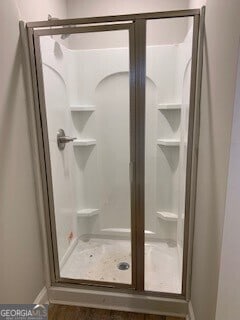 full bathroom with a stall shower and baseboards