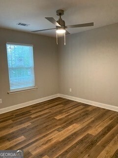 spare room with dark wood-type flooring, visible vents, baseboards, and a ceiling fan