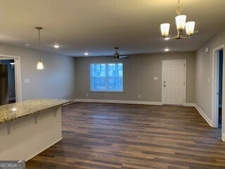 unfurnished living room featuring a notable chandelier, dark wood-style flooring, recessed lighting, and baseboards