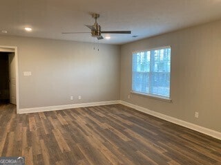 spare room with dark wood-style floors, ceiling fan, and baseboards