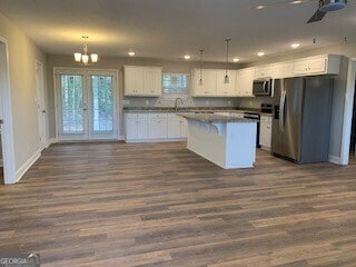 kitchen with stainless steel appliances, a kitchen island, white cabinetry, and pendant lighting