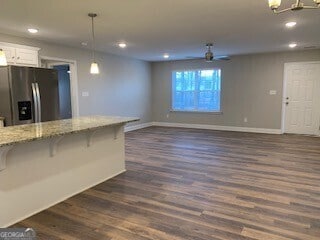 kitchen featuring white cabinetry, a kitchen breakfast bar, stainless steel fridge with ice dispenser, light stone countertops, and pendant lighting