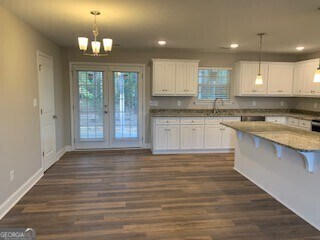 kitchen featuring white cabinets, hanging light fixtures, light stone countertops, a kitchen bar, and recessed lighting