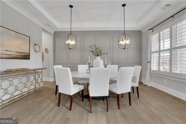 dining room with a tray ceiling and light hardwood / wood-style flooring