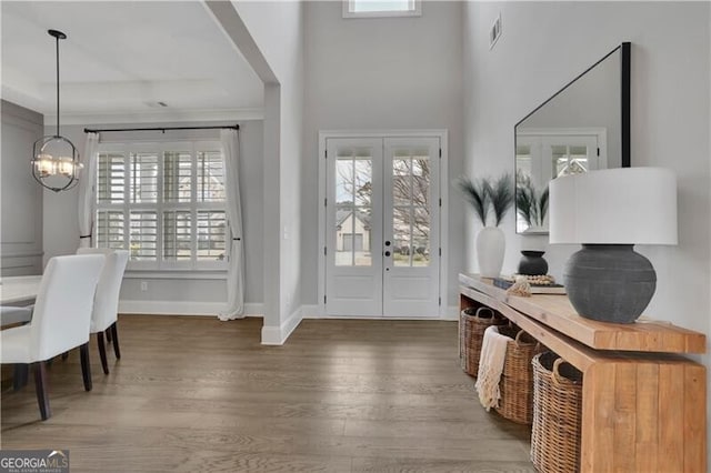 entryway with an inviting chandelier, a towering ceiling, dark hardwood / wood-style floors, and french doors