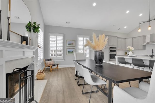 dining room with lofted ceiling and light wood-type flooring