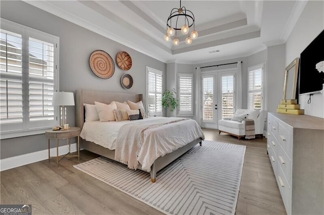 bedroom featuring a raised ceiling, crown molding, access to outside, and multiple windows