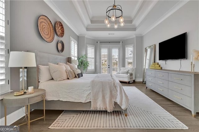 bedroom featuring ornamental molding, access to exterior, a raised ceiling, dark wood-type flooring, and french doors