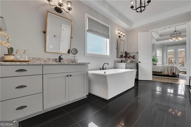 bathroom featuring an inviting chandelier, tile patterned floors, a raised ceiling, and a healthy amount of sunlight