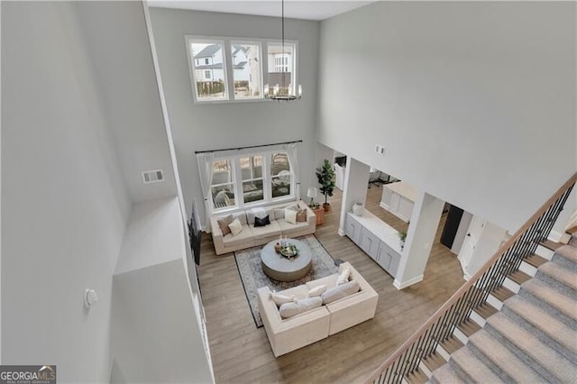 living room featuring a high ceiling, hardwood / wood-style flooring, and a notable chandelier