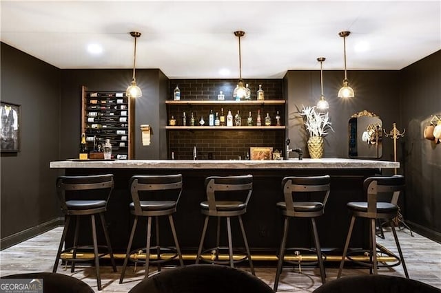 bar featuring wood-type flooring and decorative light fixtures