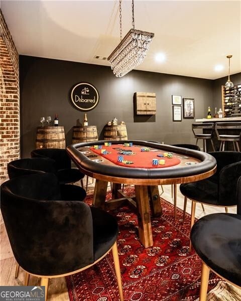 playroom with hardwood / wood-style flooring, indoor bar, and brick wall