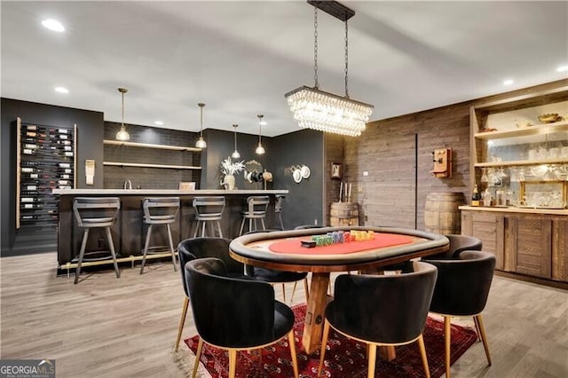 recreation room featuring wooden walls, bar area, built in features, and light wood-type flooring