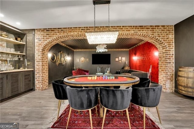 dining area with built in shelves, indoor bar, brick wall, and light hardwood / wood-style flooring