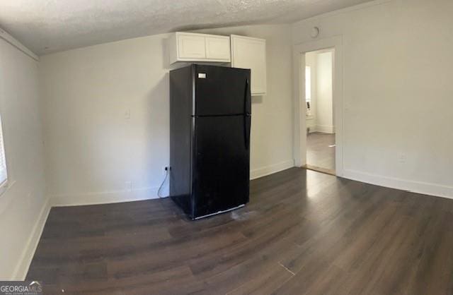 kitchen featuring black refrigerator, a textured ceiling, white cabinets, and dark wood-type flooring