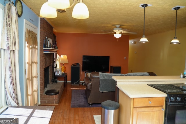 kitchen with decorative light fixtures, light hardwood / wood-style floors, a brick fireplace, and a textured ceiling