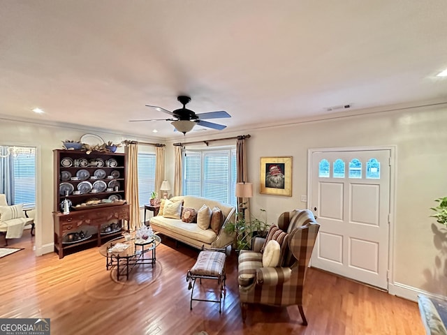 living room featuring ceiling fan, ornamental molding, and wood-type flooring