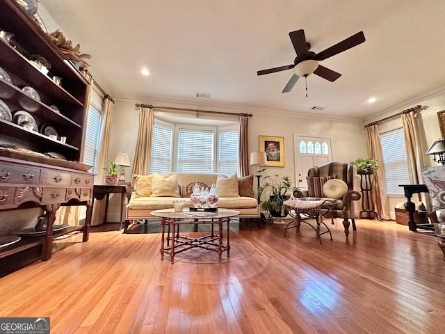 living room featuring crown molding, wood-type flooring, and ceiling fan